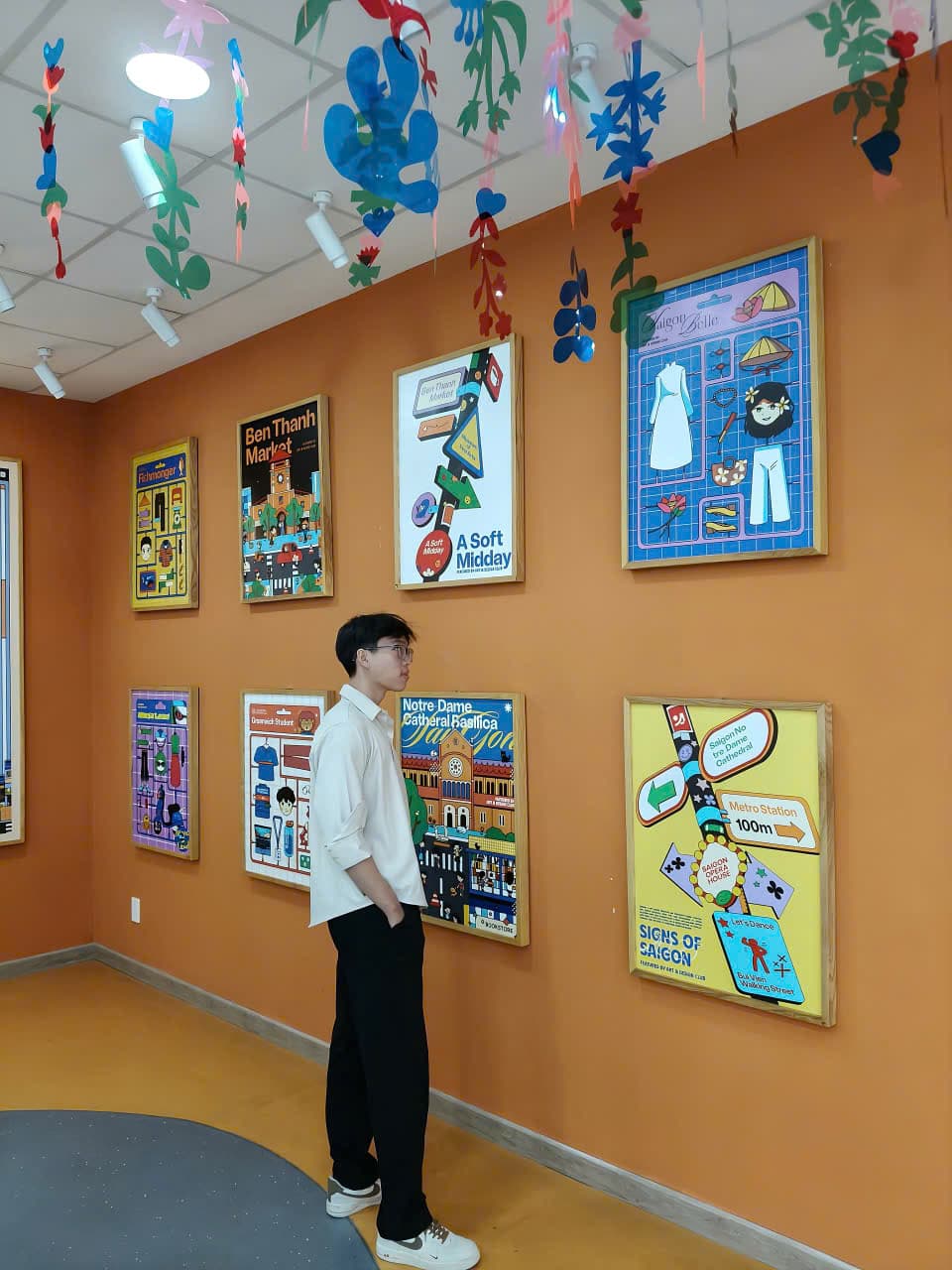 Tommy Le standing in front of a wall of illustrated Saigon posters